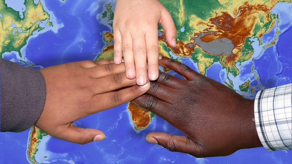 Three children's hands on top of the world